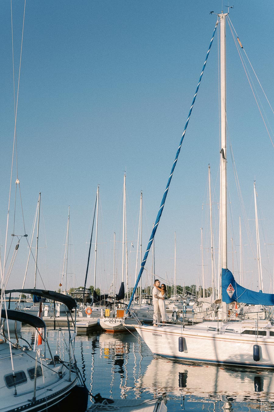 Amber and Devin embrace on a sailboat at Royal Hamilton Yacht Club marina in Hamilton, Ontario.
