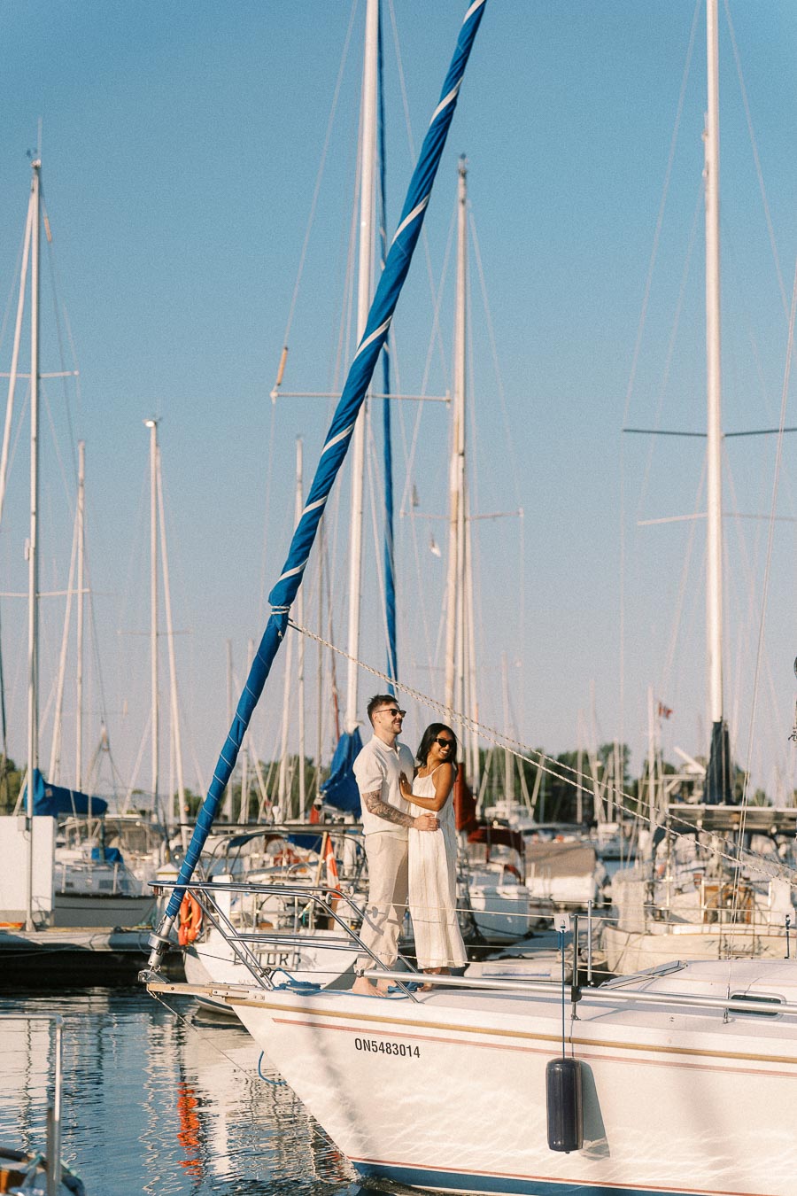 Amber and Devin standing together on a sailboat at Royal Hamilton Yacht Club marina.