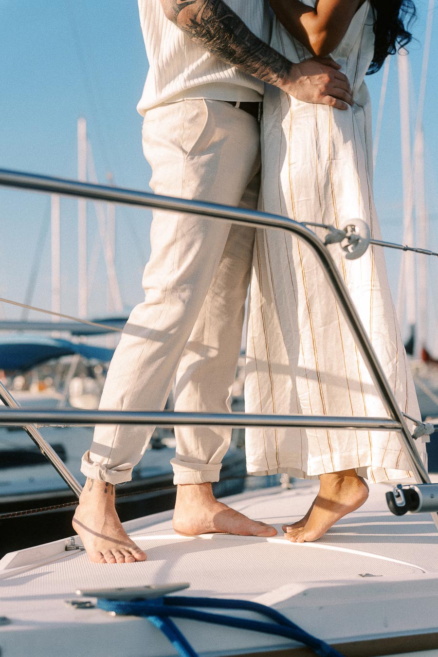 Couple standing barefoot on a sailboat deck during a yacht engagement photoshoot in Hamilton, Ontario.