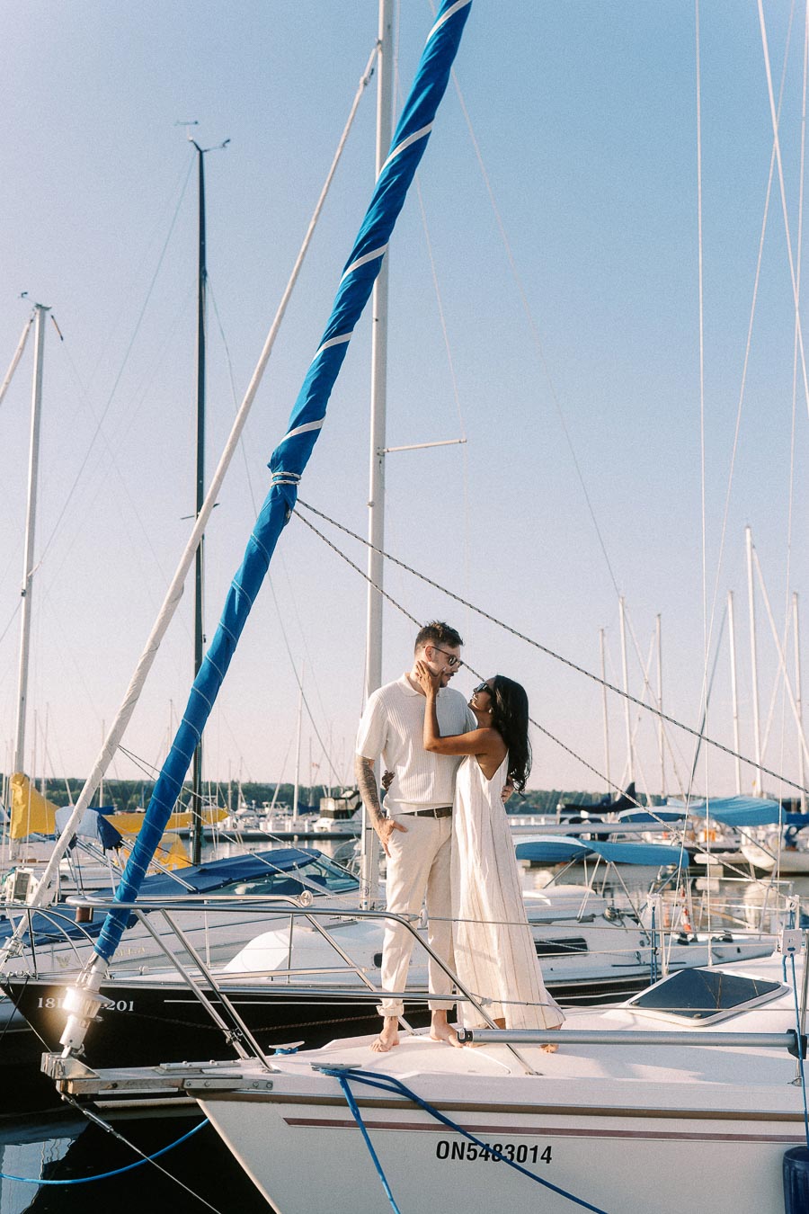 Amber and Devin embrace on a sailboat at the Royal Hamilton Yacht Club marina.