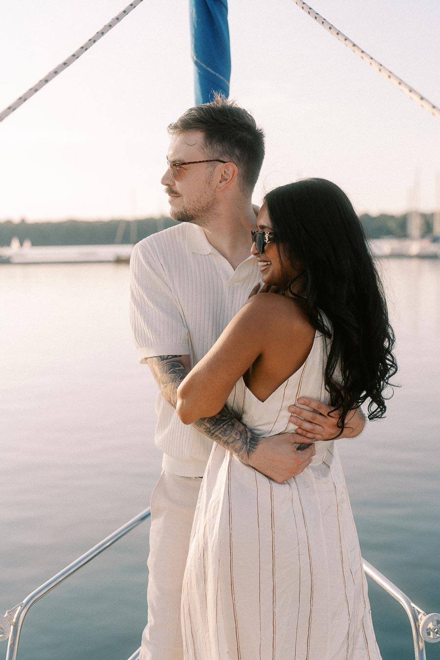 Amber and Devin embracing on a sailboat at sunset near Royal Hamilton Yacht Club.