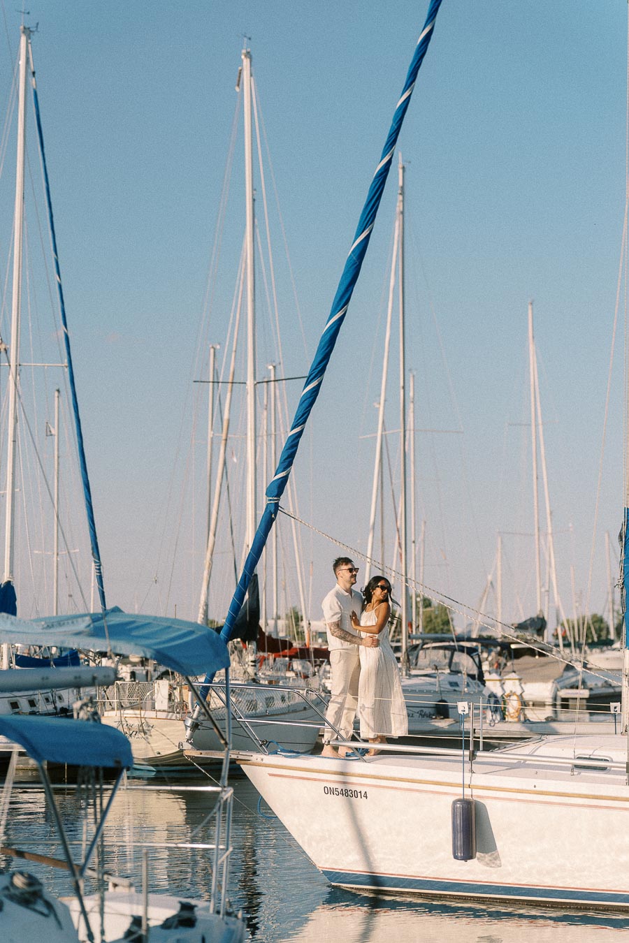 Amber and Devin standing together on a sailboat bow at Royal Hamilton Yacht Club marina.