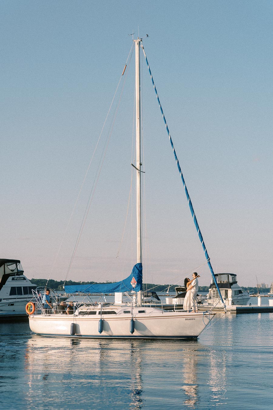 Amber and Devin embrace on a sailboat at Royal Hamilton Yacht Club marina.