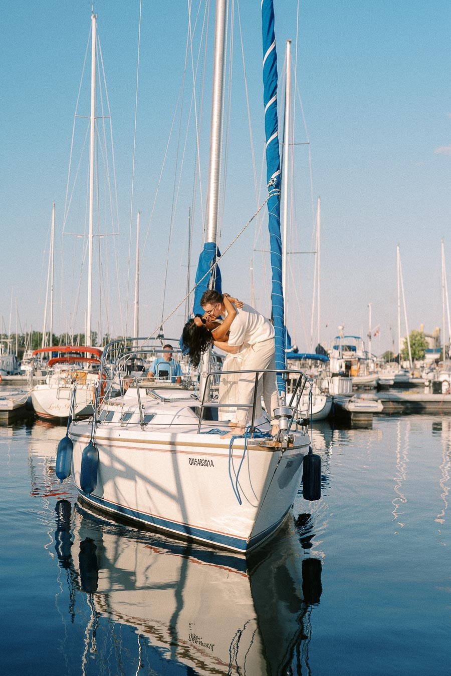 Amber and Devin embrace on a sailboat in a marina at Royal Hamilton Yacht Club.