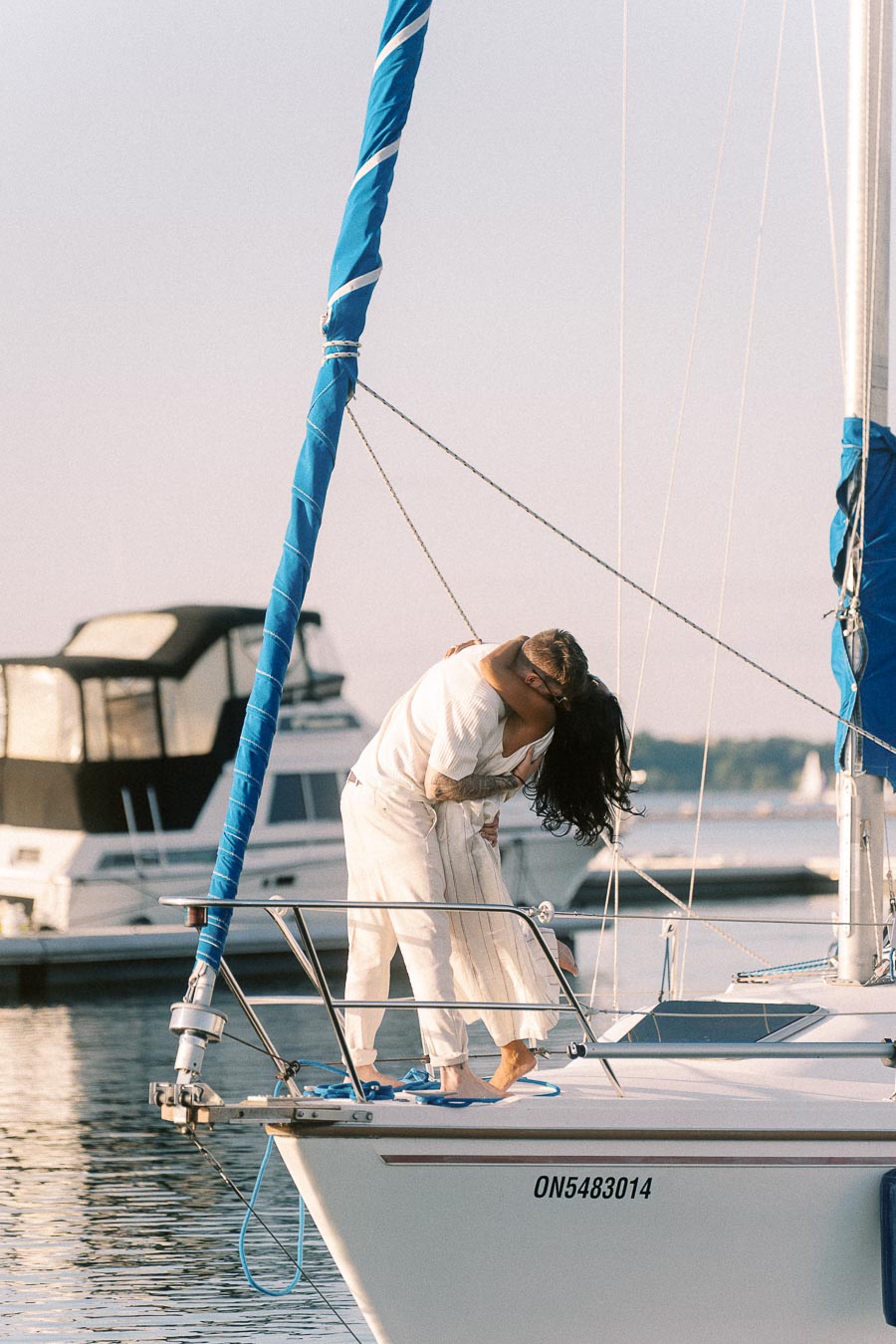 Amber and Devin kiss on the bow of a sailboat at Royal Hamilton Yacht Club.