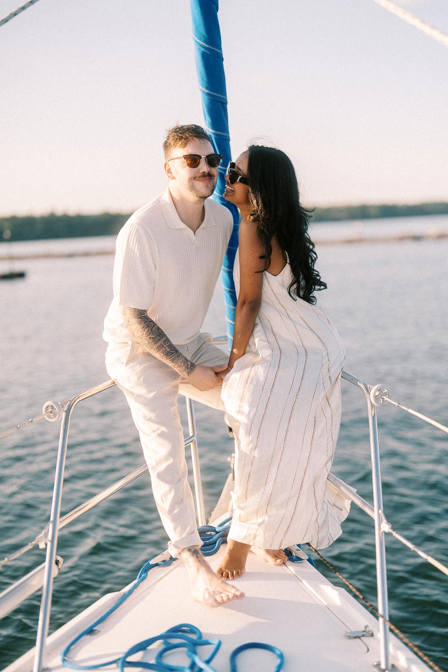 Amber and Devin holding hands on a sailboat bow during a Lake Ontario engagement session.