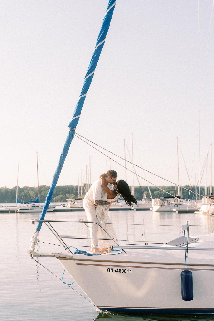 Amber and Devin kiss on a sailboat at Royal Hamilton Yacht Club marina.