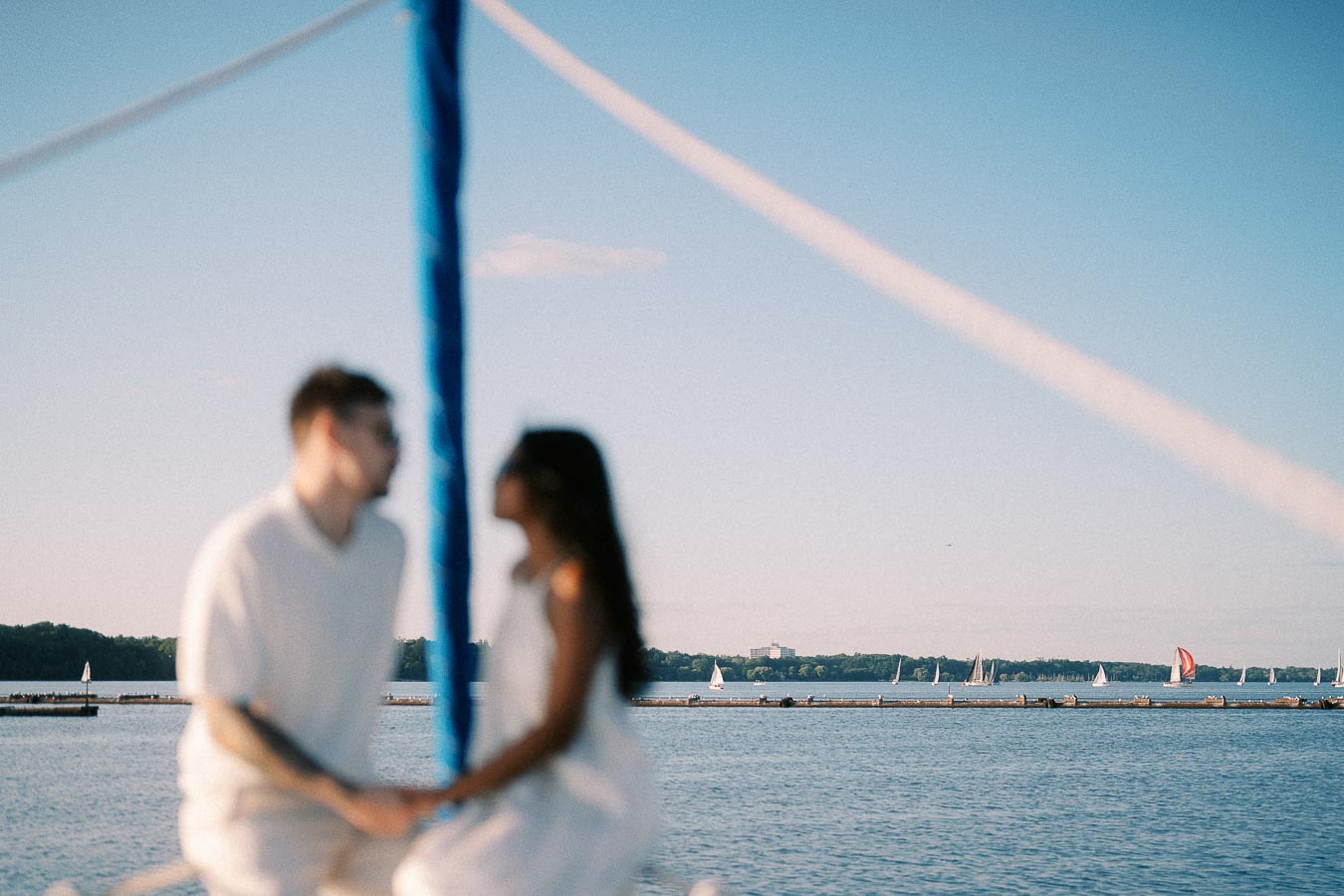Blurred couple on a sailboat with Lake Ontario sailboats in the background in Hamilton.