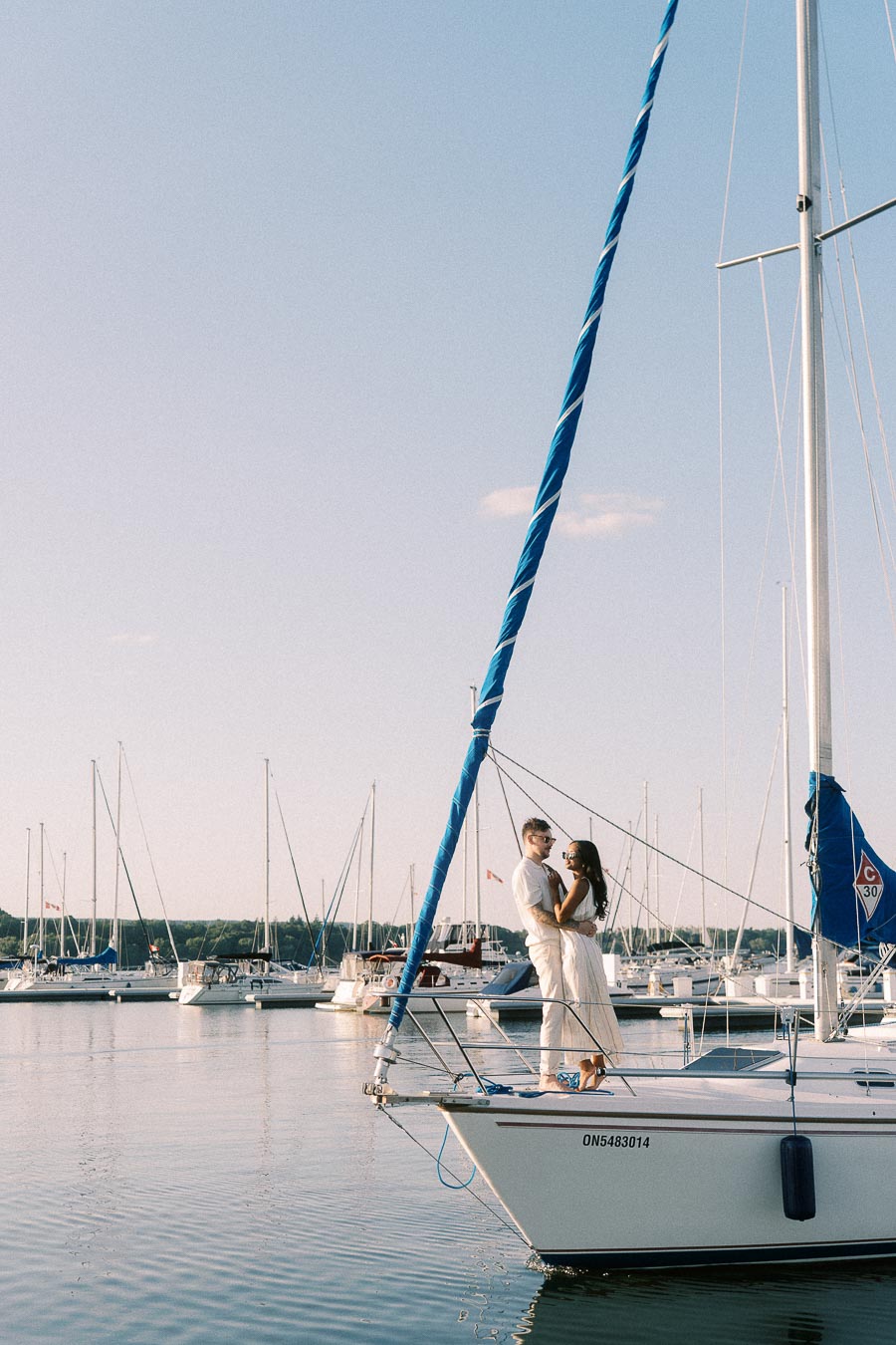 Amber and Devin embrace on a sailboat bow at Royal Hamilton Yacht Club marina.