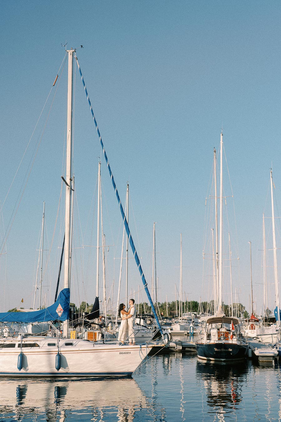 Amber and Devin embracing on a sailboat at Royal Hamilton Yacht Club marina in Ontario.