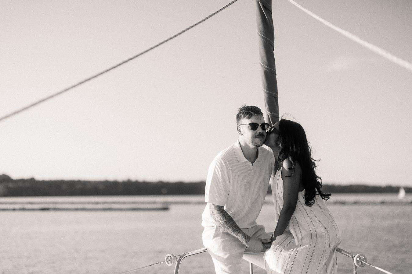 Amber and Devin kiss on a sailboat bow during their Lake Ontario engagement session.
