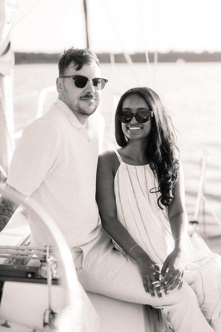 Amber and Devin wearing sunglasses aboard a sailboat during their Hamilton engagement session.