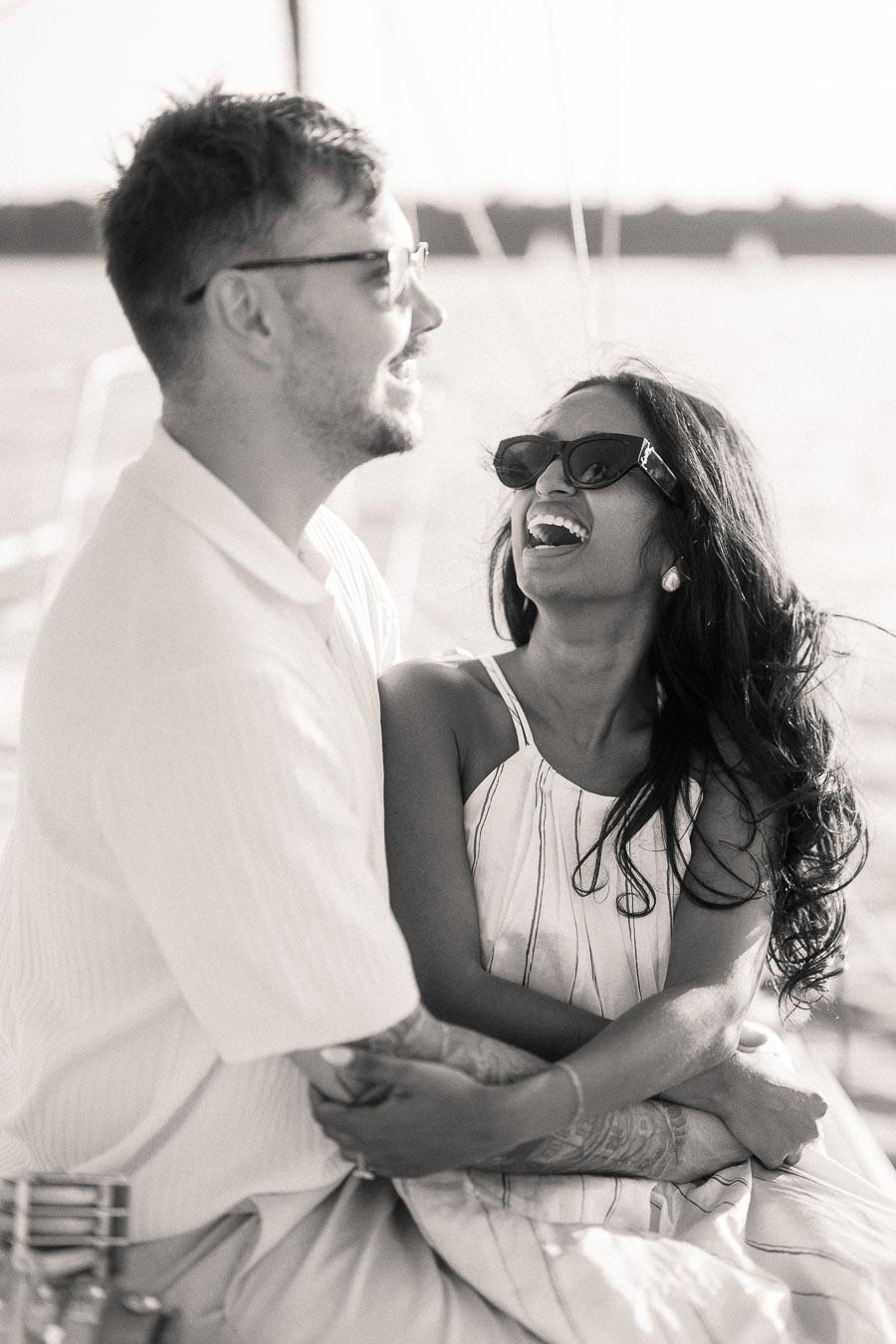 Amber and Devin laughing together on a sailboat during their Hamilton waterfront engagement session.