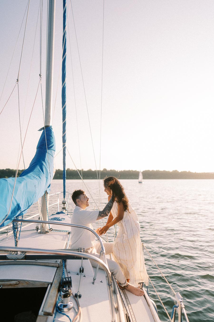 Amber and Devin sitting together on a sailboat at sunset on Lake Ontario in Hamilton.