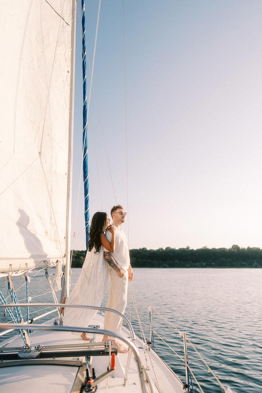 Amber and Devin standing on a sailboat deck at golden hour on Lake Ontario.