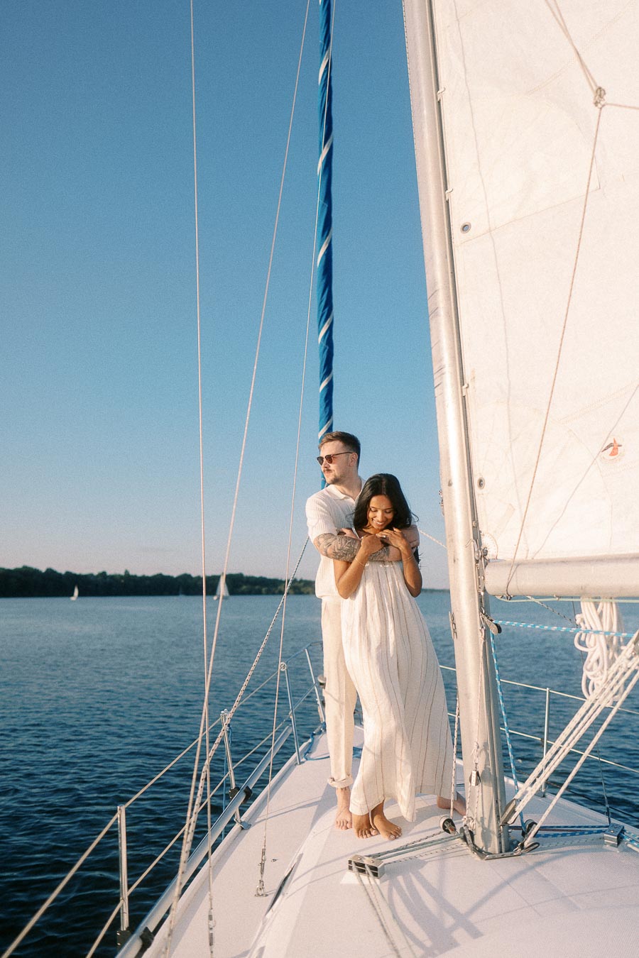 Amber and Devin embracing on a sailboat deck during a Lake Ontario engagement session.