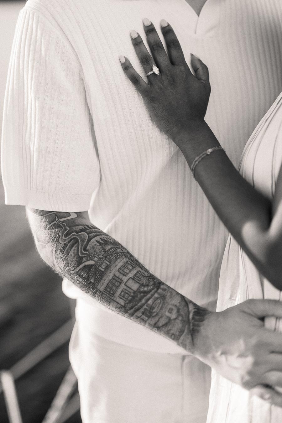 Close-up of engagement ring on woman’s hand against her partner’s chest during yacht engagement photos.