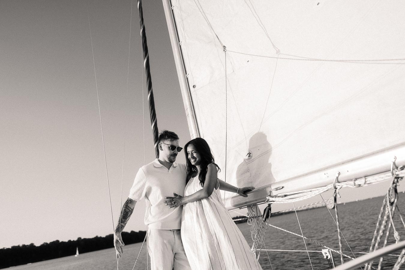 Amber and Devin standing together beside a sail on a yacht during their Lake Ontario engagement session.