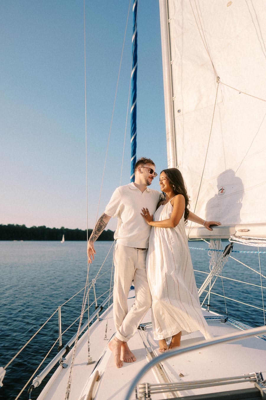 Amber and Devin embrace on a sailboat at sunset during their Lake Ontario engagement session.
