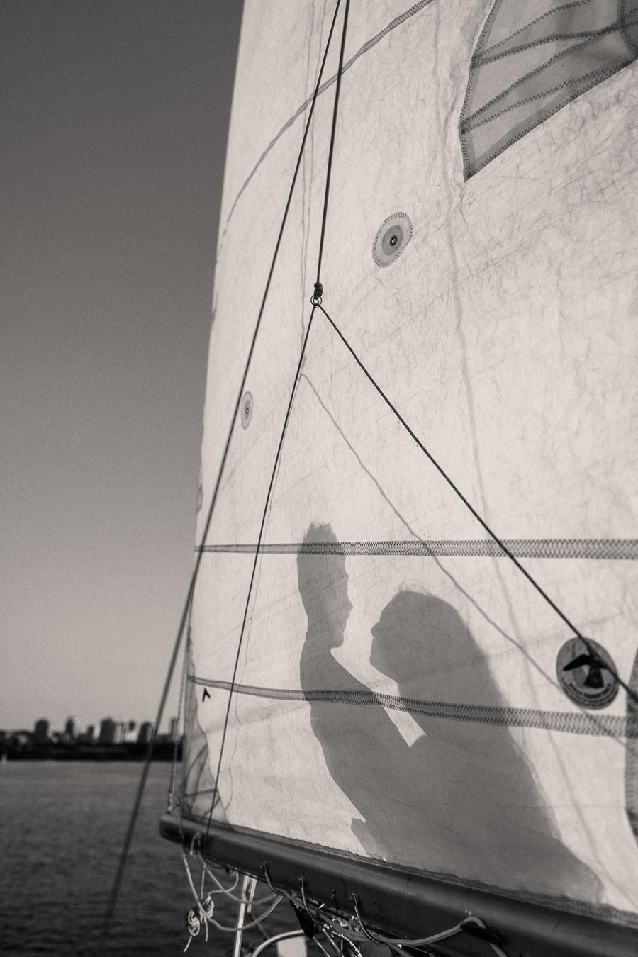 Couple’s silhouettes on a sailboat sail during a waterfront engagement session in Hamilton, Ontario.