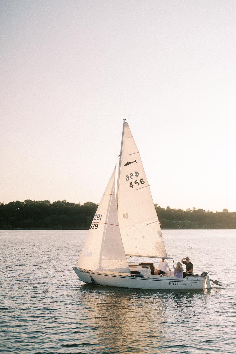 Sailboat carrying people on Lake Ontario at sunset near Royal Hamilton Yacht Club.