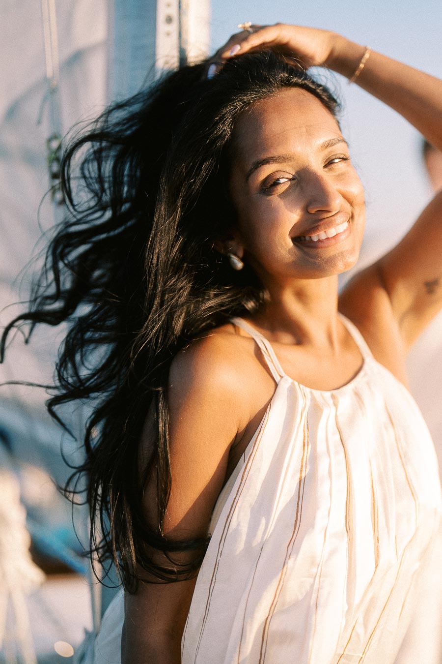 Amber smiling on a sailboat in warm golden hour light during an engagement session.
