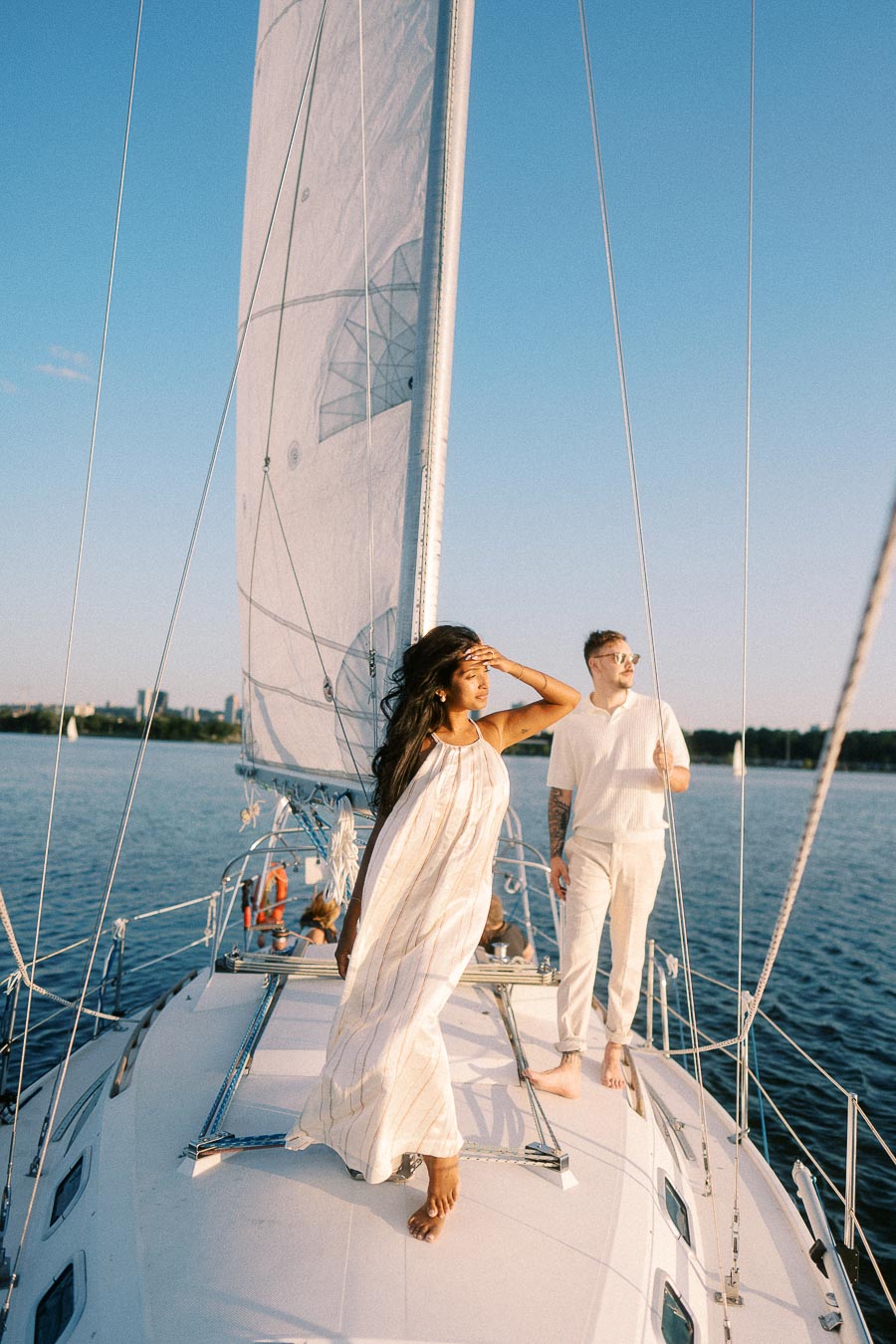 Amber and Devin standing barefoot on a sailboat deck during a Lake Ontario engagement session.