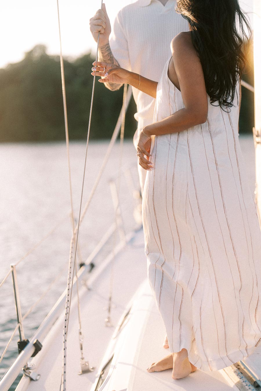 Couple standing barefoot on a sailboat deck during a golden hour engagement session in Hamilton.