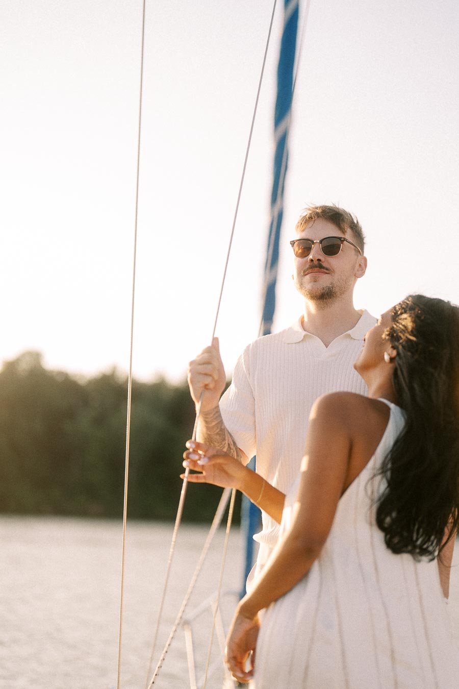 Amber and Devin standing by sailboat rigging during golden hour on Lake Ontario.