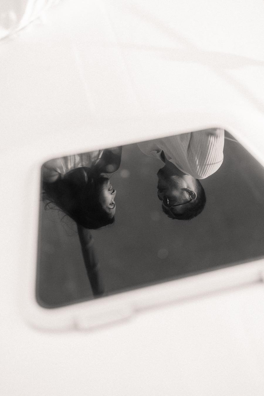 Black and white reflection of Amber and Devin in a sailboat window during their engagement session.