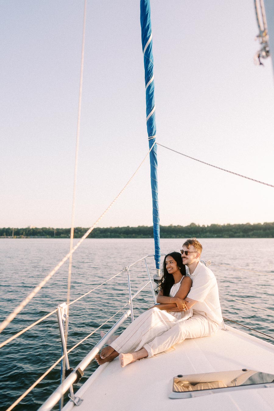 Amber and Devin cuddle on a sailboat bow during a Lake Ontario engagement session.