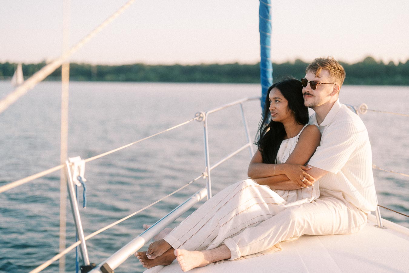 Amber and Devin sitting together on a sailboat deck at golden hour on Lake Ontario.