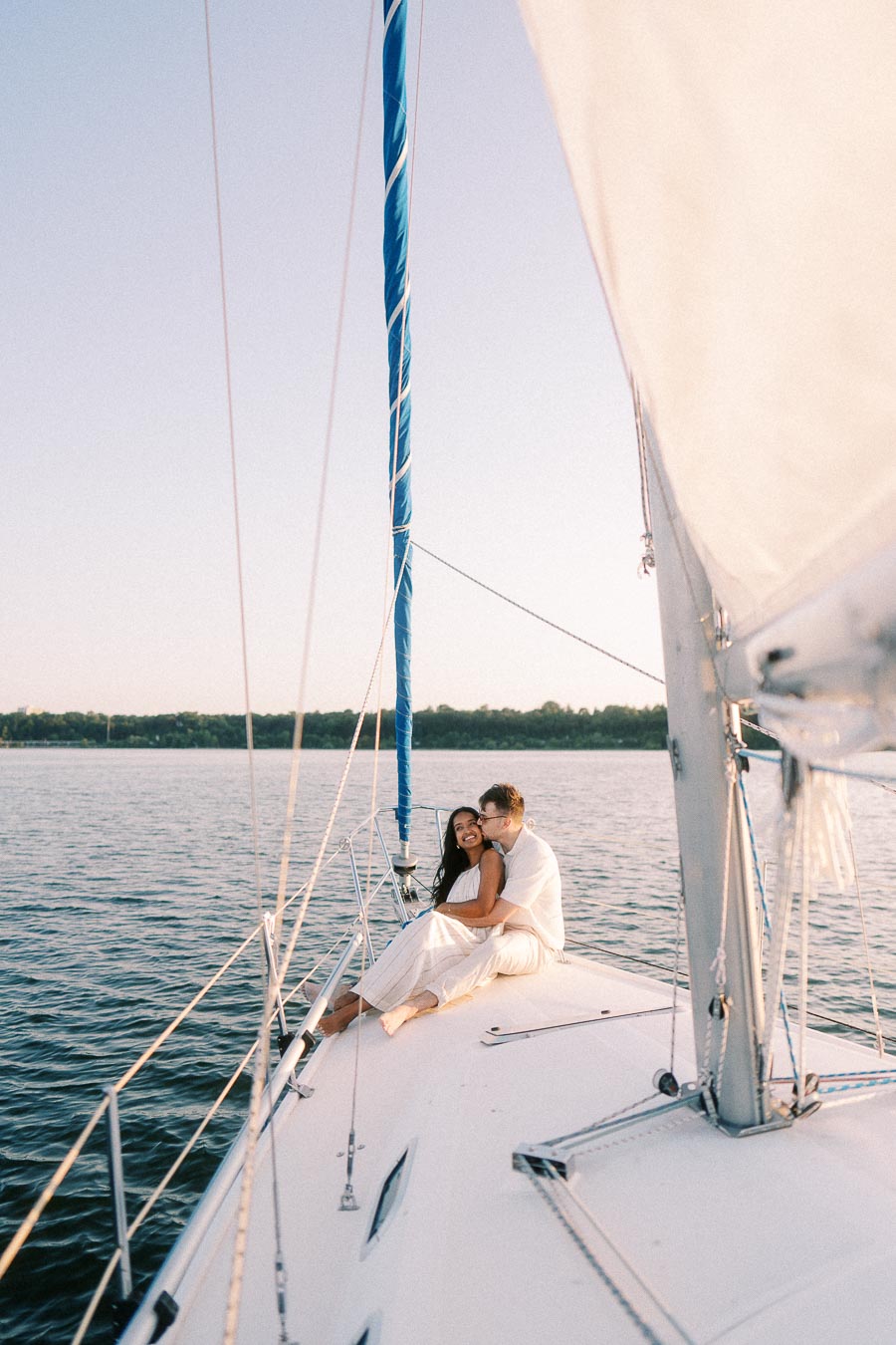 Amber and Devin cuddling on a sailboat bow during a Lake Ontario engagement session.