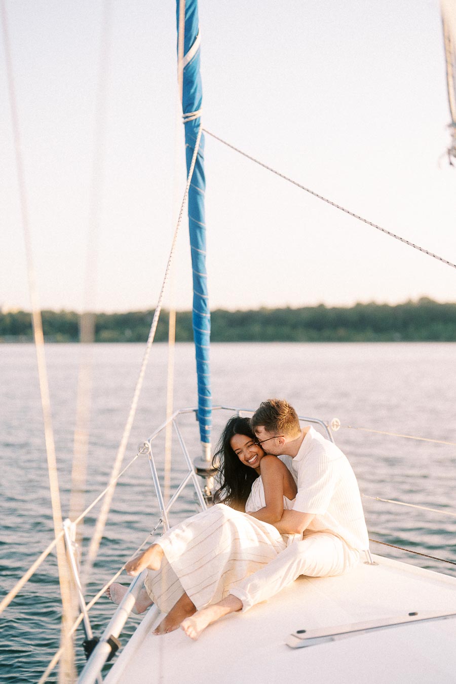 Amber and Devin cuddling on a sailboat deck during a Lake Ontario engagement session.
