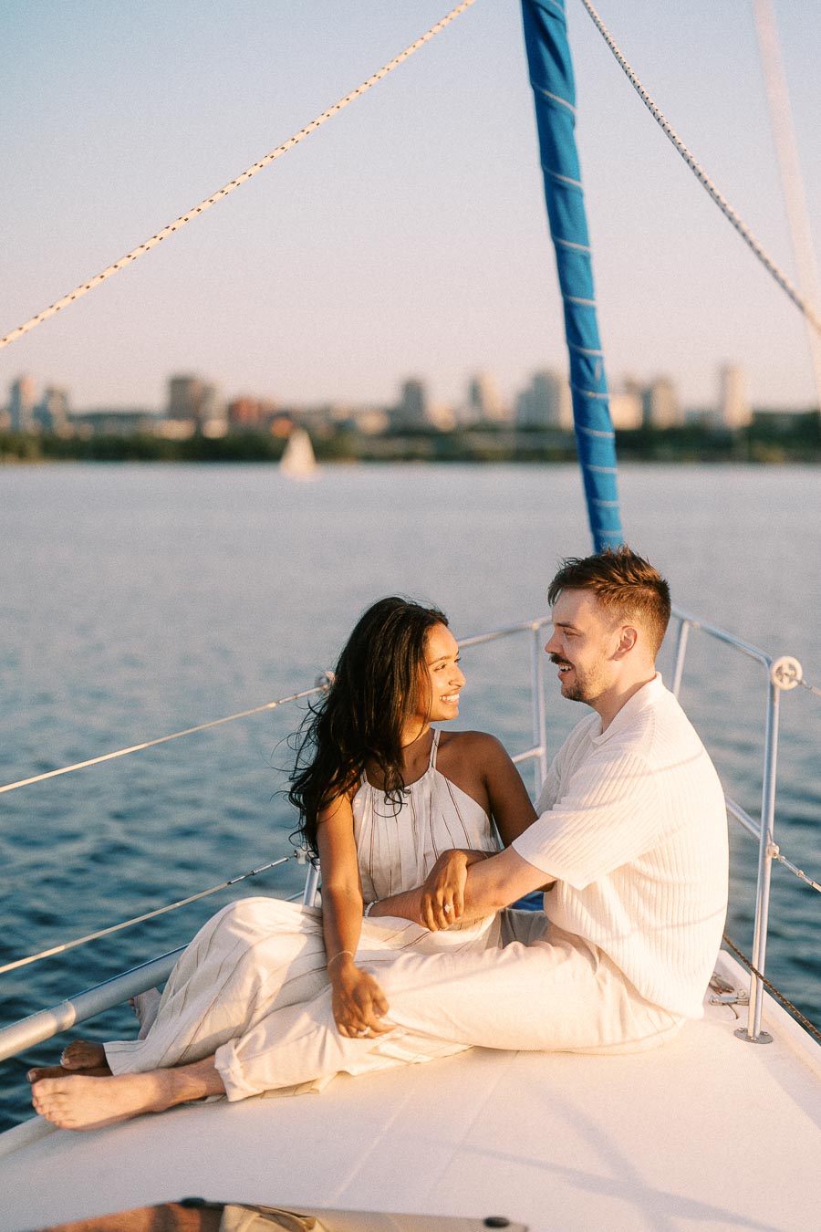 Amber and Devin sit on a sailboat deck at golden hour on Lake Ontario.