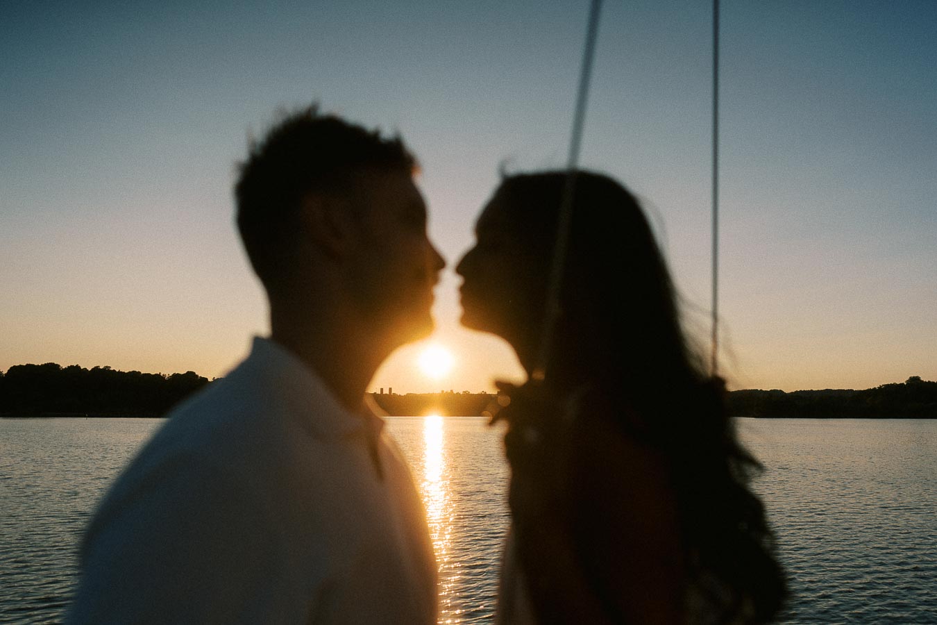 Silhouetted couple kissing on a sailboat at sunset over Lake Ontario in Hamilton.
