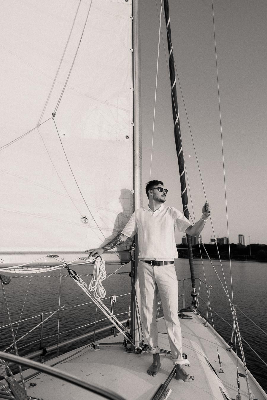 Devin stands on a sailboat deck holding a rope on Lake Ontario near Hamilton.