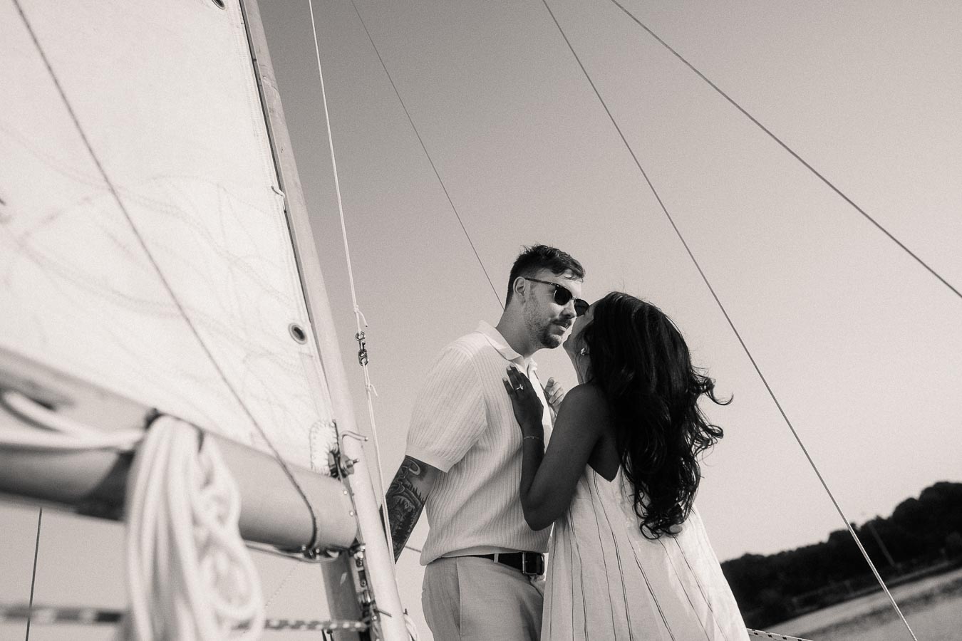 Amber and Devin embrace beside a sailboat mast during their yacht engagement photos in Hamilton, Ontario.