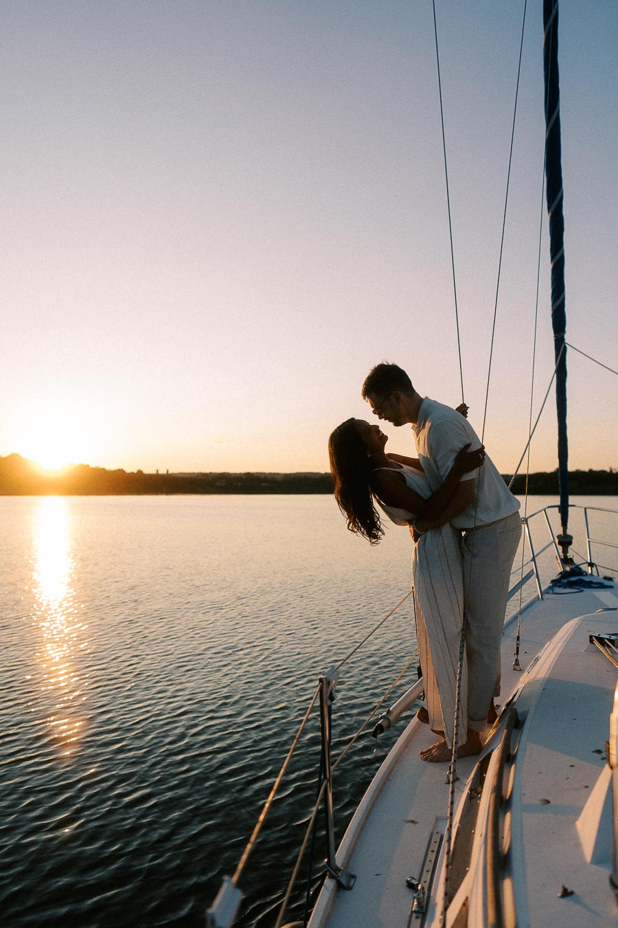 Amber and Devin embrace on a sailboat at sunset during their Lake Ontario engagement session.