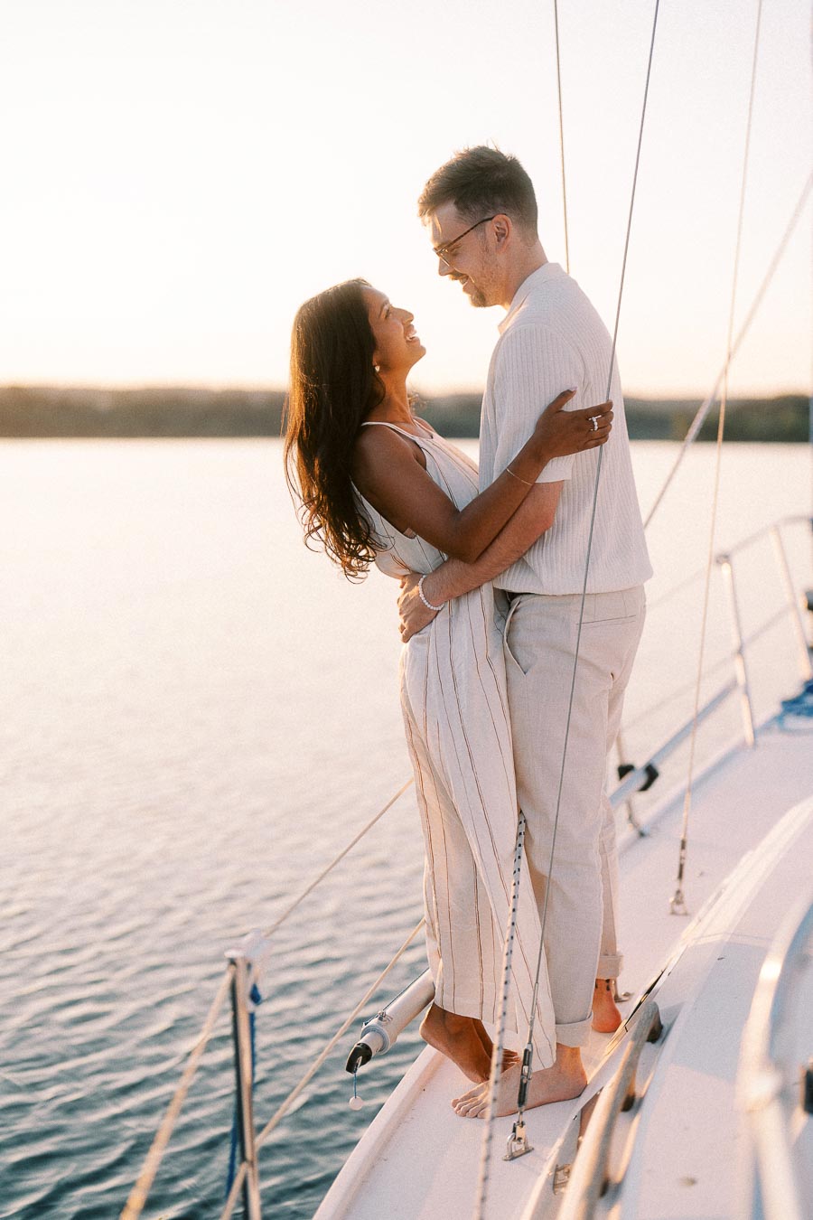 Amber and Devin embrace on a sailboat at sunset during their Lake Ontario engagement session.