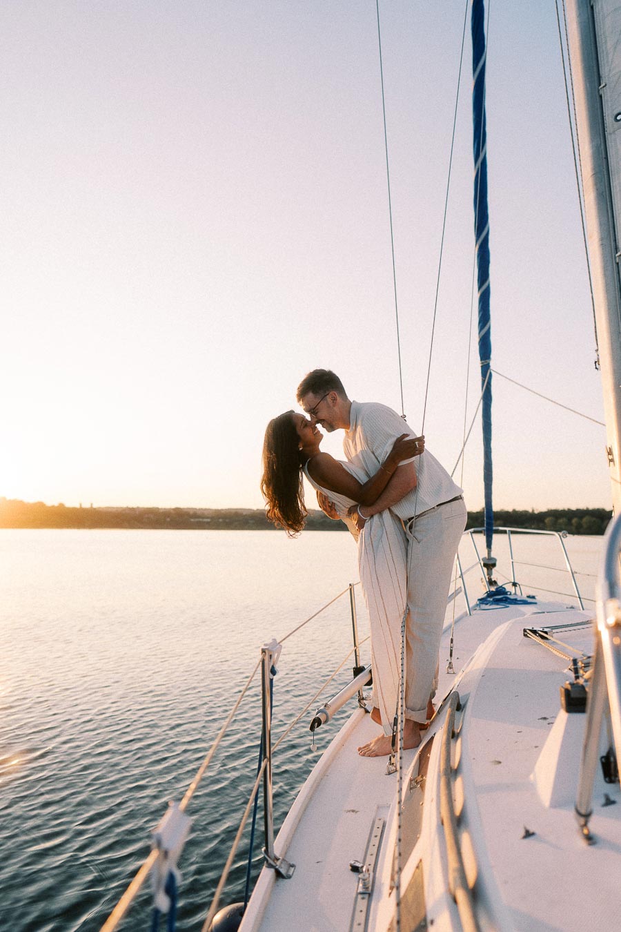 Amber and Devin kissing on a sailboat deck at sunset on Lake Ontario.