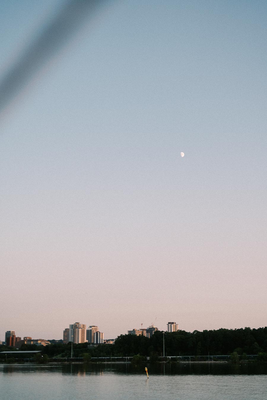 Moon over Hamilton waterfront skyline and Lake Ontario at dusk.