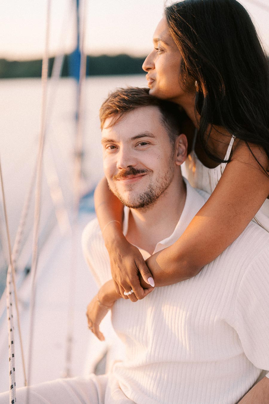 Amber and Devin cuddle on a sailboat during a golden hour engagement session in Hamilton, Ontario.