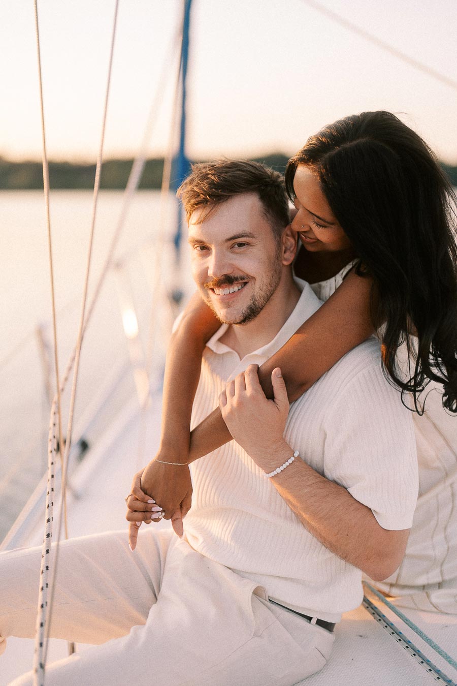Amber and Devin embrace on a sailboat during golden hour in Hamilton, Ontario.