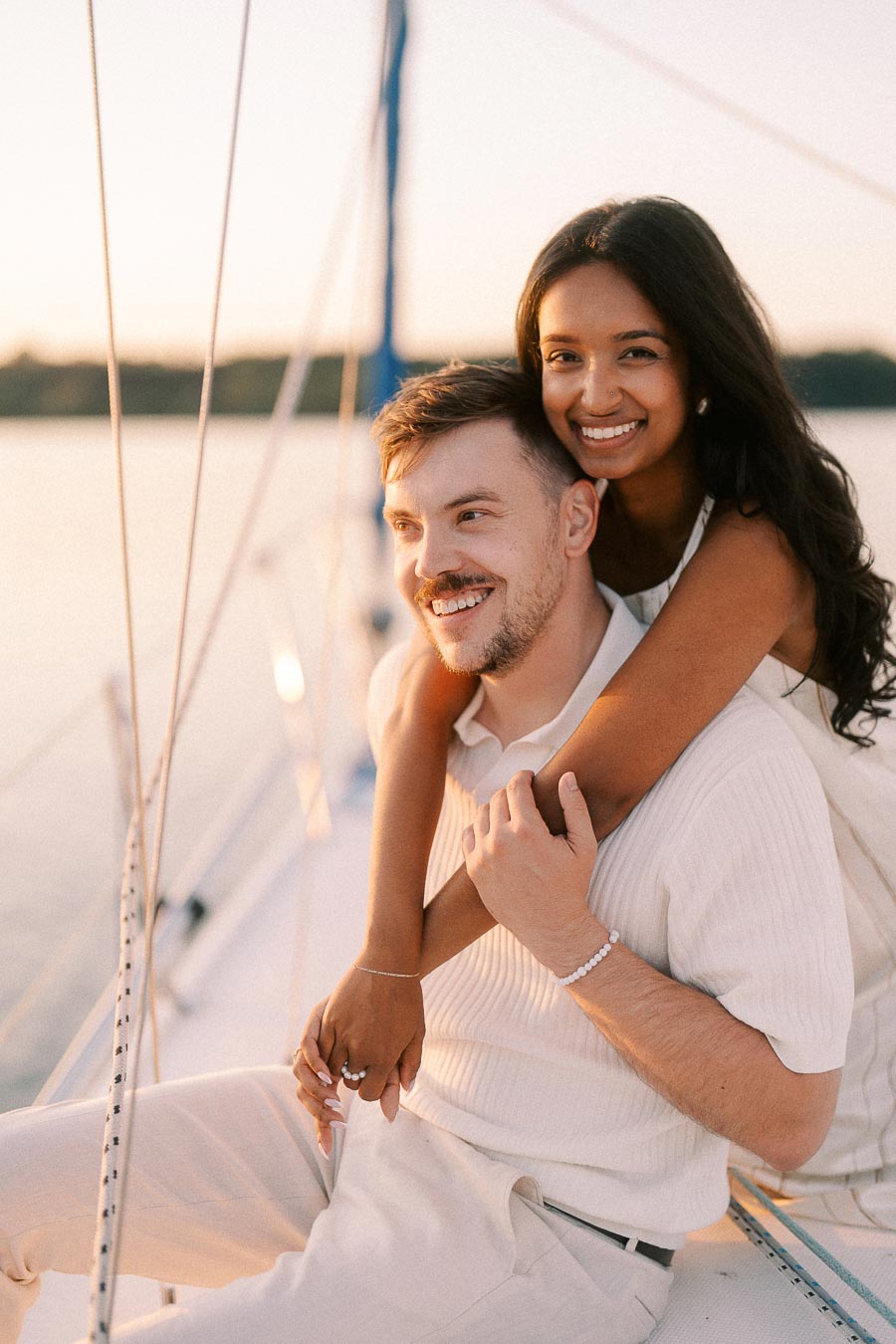 Amber and Devin smiling together on a sailboat during golden hour at Royal Hamilton Yacht Club.
