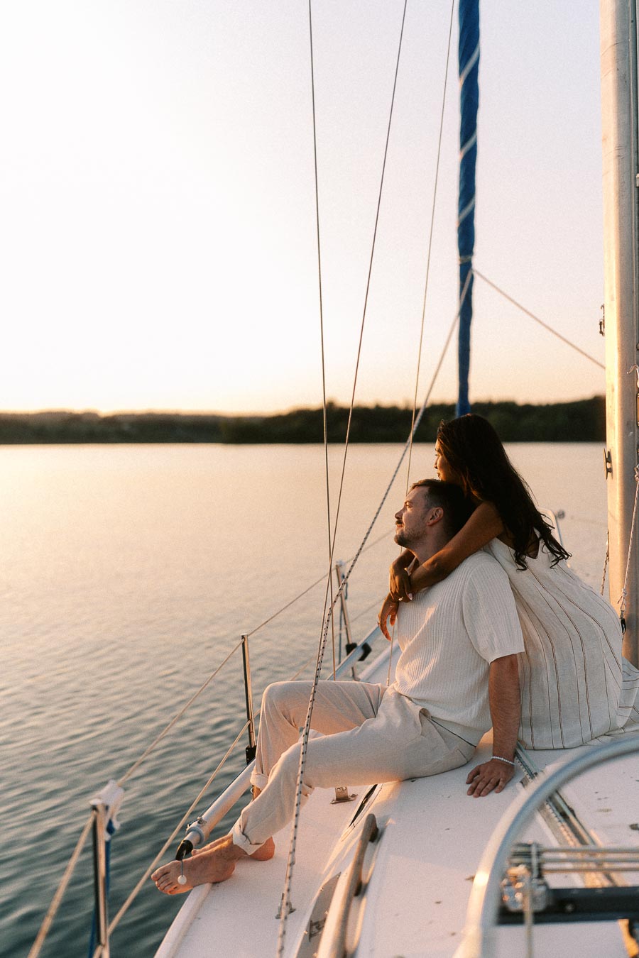 Amber and Devin sitting on a sailboat deck at sunset on Lake Ontario.
