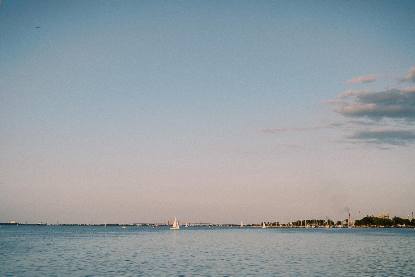 Sailboats on Lake Ontario near Hamilton marina at sunset with a pastel sky.