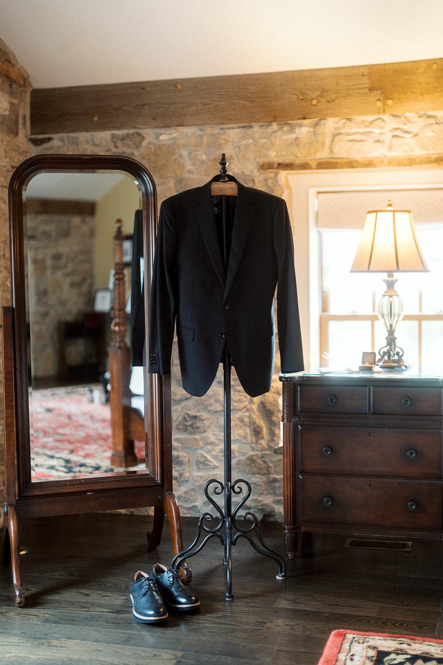 Black suit jacket and dress shoes displayed in a rustic room before an engagement photoshoot