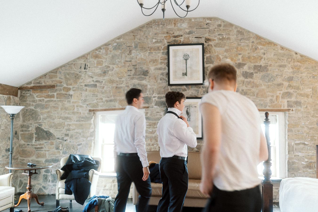 Three men getting dressed in a stone-walled room before a photoshoot