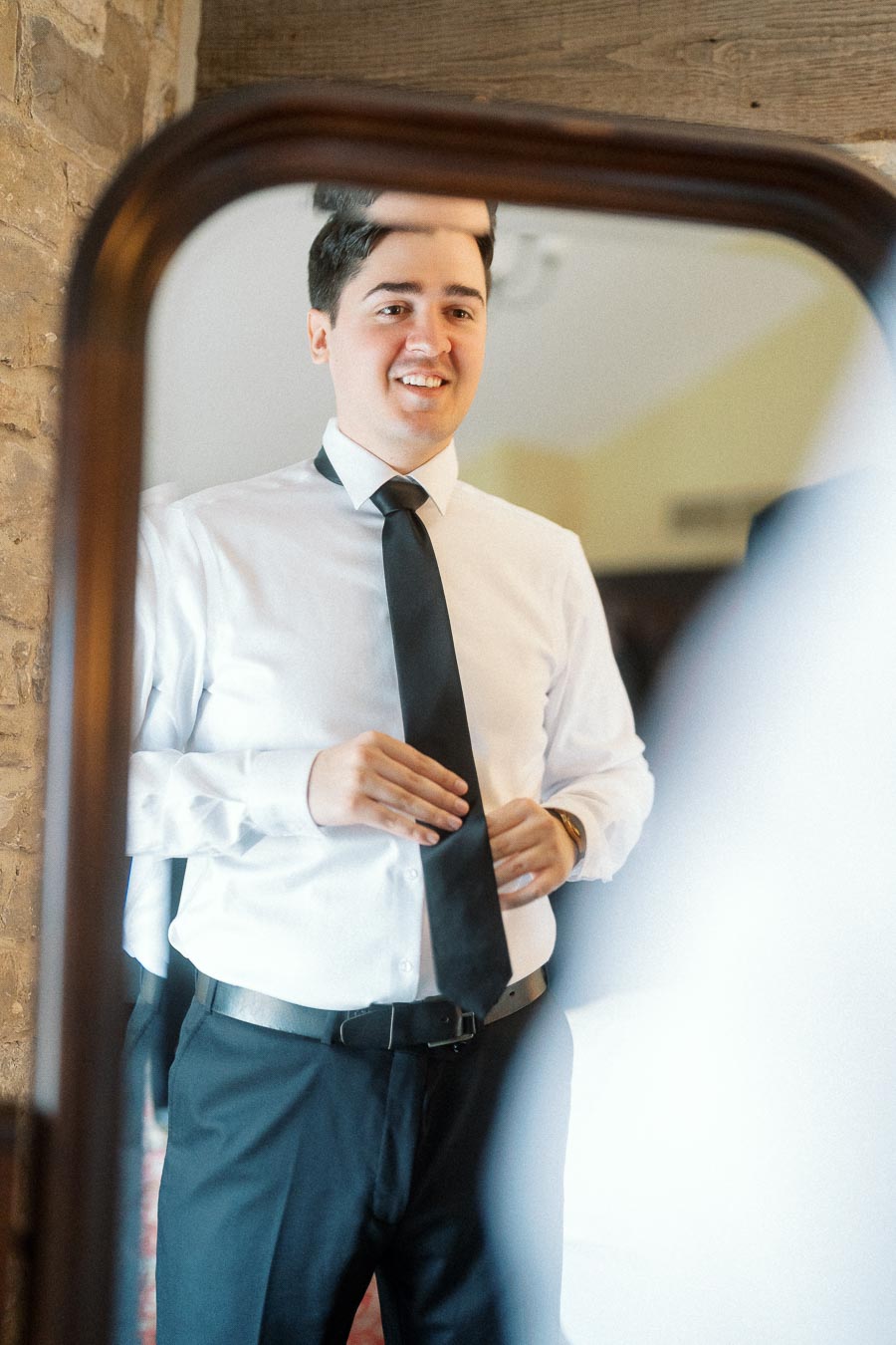 Man in white shirt and black tie reflected in a mirror